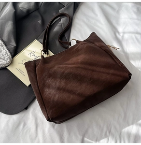 Close-up of a dark brown leather tote bag with gold metal rings and minimalist design