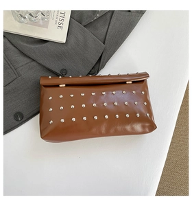 Détail d'une pochette enveloppe en similicuir marron avec rivets argentés et fermoir doré