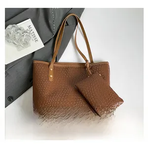 Vista piatta della borsa tote marrone intrecciata con pochette coordinata e tracolle lunghe