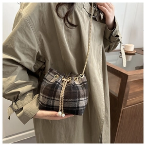 Detail of wool plaid bucket bag with gold chain strap and pearl drawstring charm