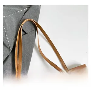 Dettaglio di una borsa tote marrone con texture a coccodrillo e doppi manici piatti a spalla