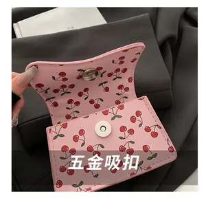Close-up of pink shoulder bag with cherry print featuring a silver magnetic snap button