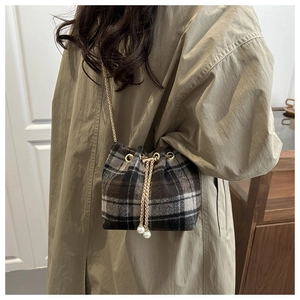 Detail of checkered bucket bag with drawstring closure and elegant pearl accents