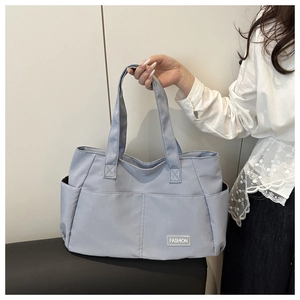 Dettaglio della borsa tote in nylon lilla con tasca laterale ed etichetta per il lavoro