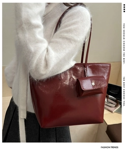Detail of burgundy glossy leather tote bag with a matching mini pouch on a model