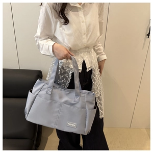 Dettaglio della borsa tote in nylon azzurro con tasche laterali e logo per il pendolare