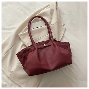 Detail view of burgundy leather tote showing litchi grain texture and gold metal hardware