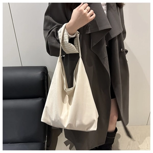 Grand sac fourre-tout beige porté sur un manteau gris montrant le style minimaliste chic