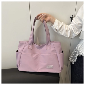 Detail of light purple nylon tote bag featuring front pockets and a fashion patch