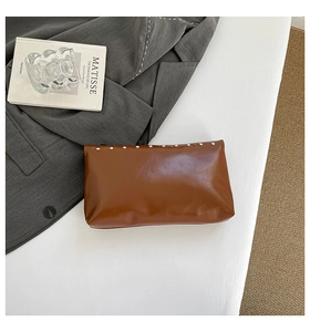 Détails de la pochette en cuir marron avec des clous argentés sur une surface plane