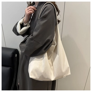 Sac hobo beige minimaliste porté par un mannequin avec une silhouette souple et spacieuse