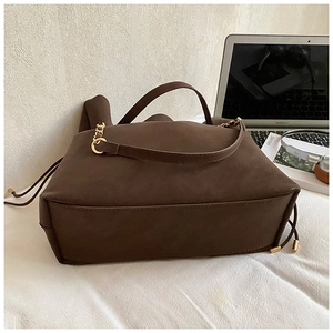 Detail view of brown suede bucket bag with gold chain strap and elegant ring hardware
