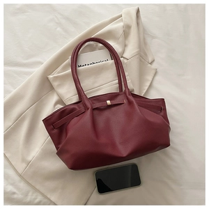 Detailed macro view of burgundy lychee textured leather tote with elegant bow and gold buckle