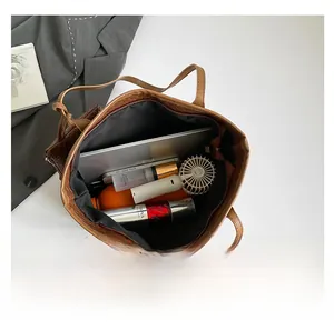 Dettaglio interno della borsa tote intrecciata marrone con ampia capacità per laptop e trucco
