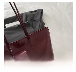 Detailed macro of burgundy tote bag with shiny oil wax leather texture and mini bag charm