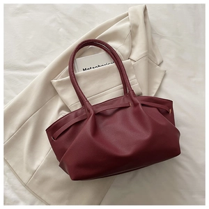 Detail of burgundy pleated tote bag showing lychee grain leather texture on beige blazer