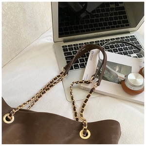 Detail of deep brown tote bag featuring golden chain straps and soft matte leather texture