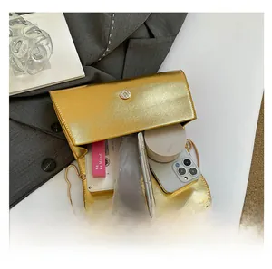 Détail montrant l'intérieur spacieux du sac à chaîne doré avec téléphone et rouge à lèvres