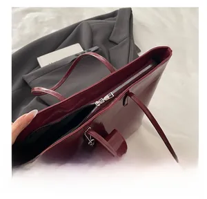 Close-up of smooth silver zipper detail on burgundy high-gloss faux leather tote bag