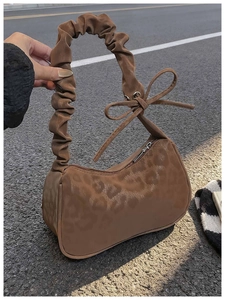 Détail du sac hobo montrant la texture léopard marron et la poignée avec nœud décoratif
