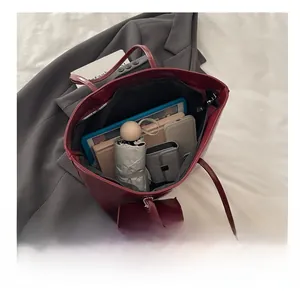 Macro view of burgundy leather tote bag showing spacious interior with tablet and daily items