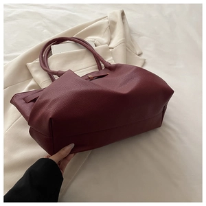 Detailed close-up of burgundy leather tote showing rich pebbled texture and wide bottom