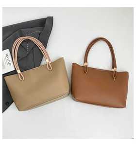 Chic khaki and brown tote bags displayed on a grey blazer with an art book backdrop