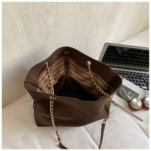Interior view of brown bucket bag with chain strap, striped lining, and magnetic closure