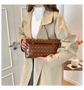 Close-up of a dark brown leather clutch featuring silver rivets and a fold-over design
