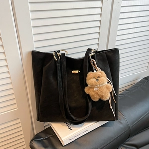 Classic black large tote bag with matte leather and golden hardware on white books