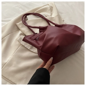 Detail of burgundy leather tote bag with lychee texture and slim double handles
