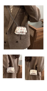 Detail view of mini crossbody bag with cherry print and delicate silver chain strap