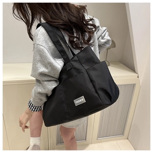 Close-up of black canvas tote bag with fashion tag on a model in a minimalist setting