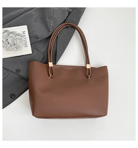 Close-up of brown tote bag showing smooth synthetic leather and golden square hardware