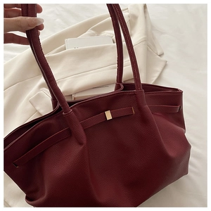 Detail of burgundy lychee leather texture and gold buckle on a stylish tote bag