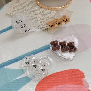 Detail of heart-shaped acrylic hair claws with glitter finish and cute 3D bears
