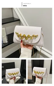 Gros plan sur un sac blanc avec garniture métallique dorée ondulée et bandoulière