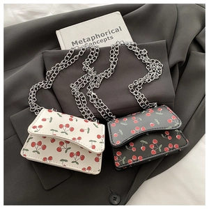Close-up of mini square chain bags with cherry pattern in creamy white and black PU leather