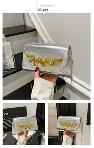 Détail du sac boîte argenté avec garniture métallique dorée fluide et texture fine