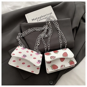 Detail of mini white chain bags with strawberry and lip prints on a blazer background