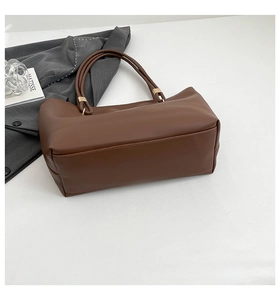 Detail of a brown PU leather tote bag with gold metal buckles and large capacity design