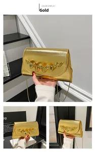 Détail d'un sac bandoulière doré métallisé avec garniture ondulée 3D et chaîne fine