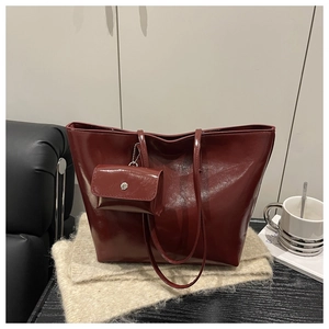 Detail view of burgundy faux leather tote bag with glossy finish and matching mini pouch