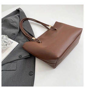 Close-up of deep brown leather tote bag showing elegant golden buckles and stitching details