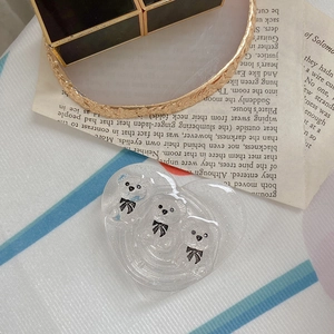 Detail of heart-shaped glitter phone stand with three 3D white bears on fabric background