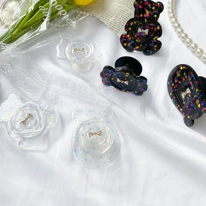 Detail of glitter bow phone grips in cute shapes on a romantic aesthetic background