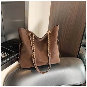 Brown faux suede bucket bag with gold chain strap on a vintage leather chair