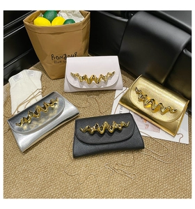 Vue à plat de sacs enveloppes en blanc or argent et noir avec garniture métallique