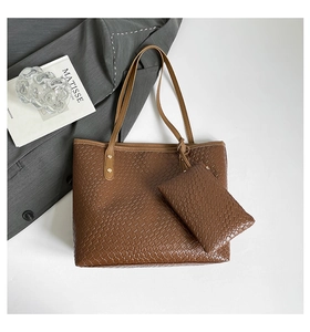 Detail of dark brown woven tote bag set with matching pouch on a luxury minimalist backdrop