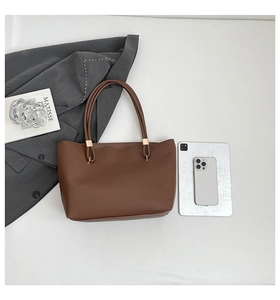 Detail of a brown tote bag with gold hardware and smooth matte leather texture